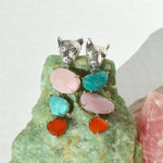 Silver leopard shaped earrings with colorful stones on a green stone background
