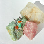 Silver earrings with colorful stones on a background of rough gemstones