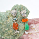 Pair of silver leopard shaped earrings with colorful stones on a textured stone background