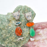 Pair of silver leopard shaped earrings with colorful stones on a textured stone background
