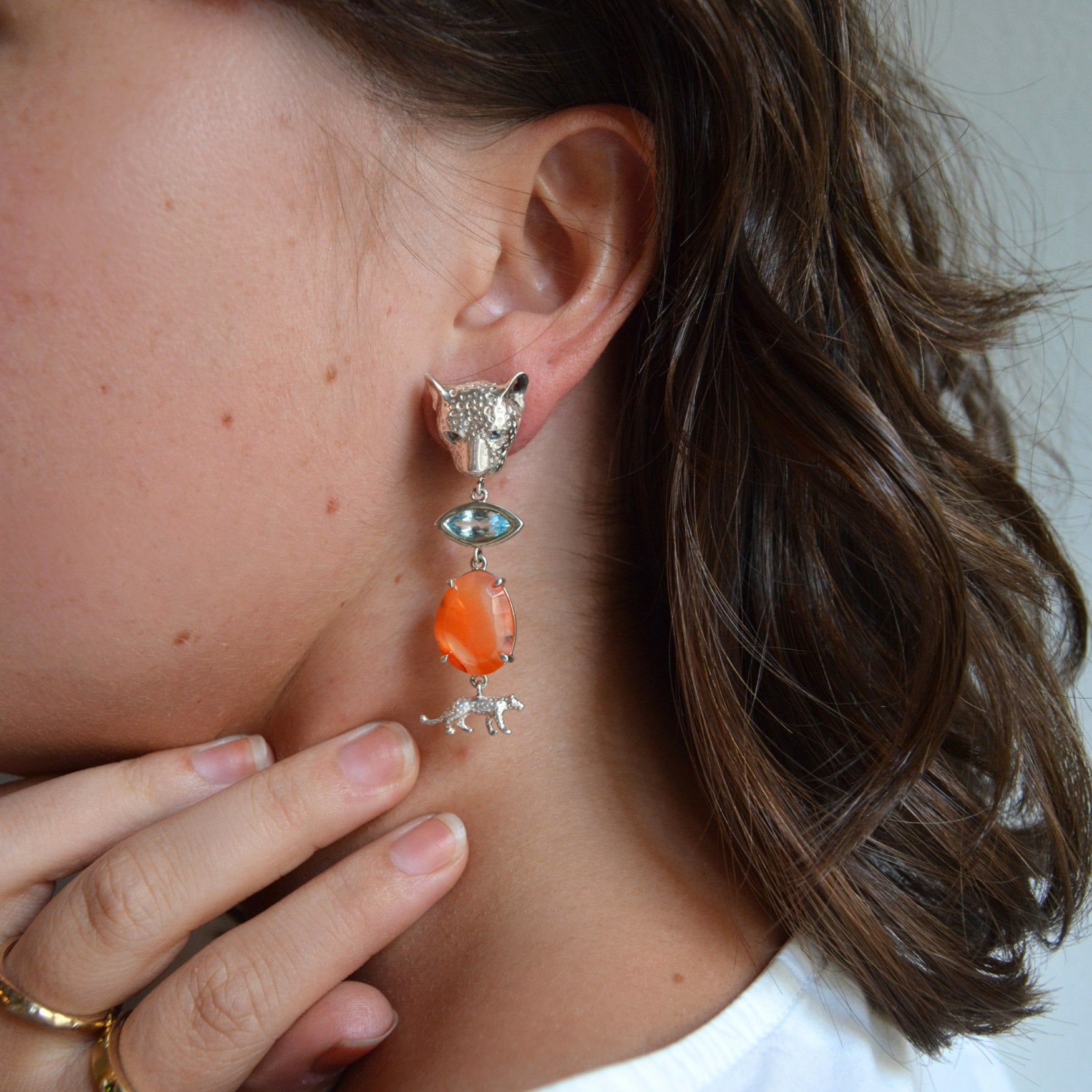 Close-up of a person wearing a colorful earring with a leopard design.