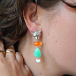 Close-up of a person wearing colorful leopard themed earrings  with a blurred background