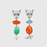 Pair of leopard shaped earrings with colored gemstones on a light grey background