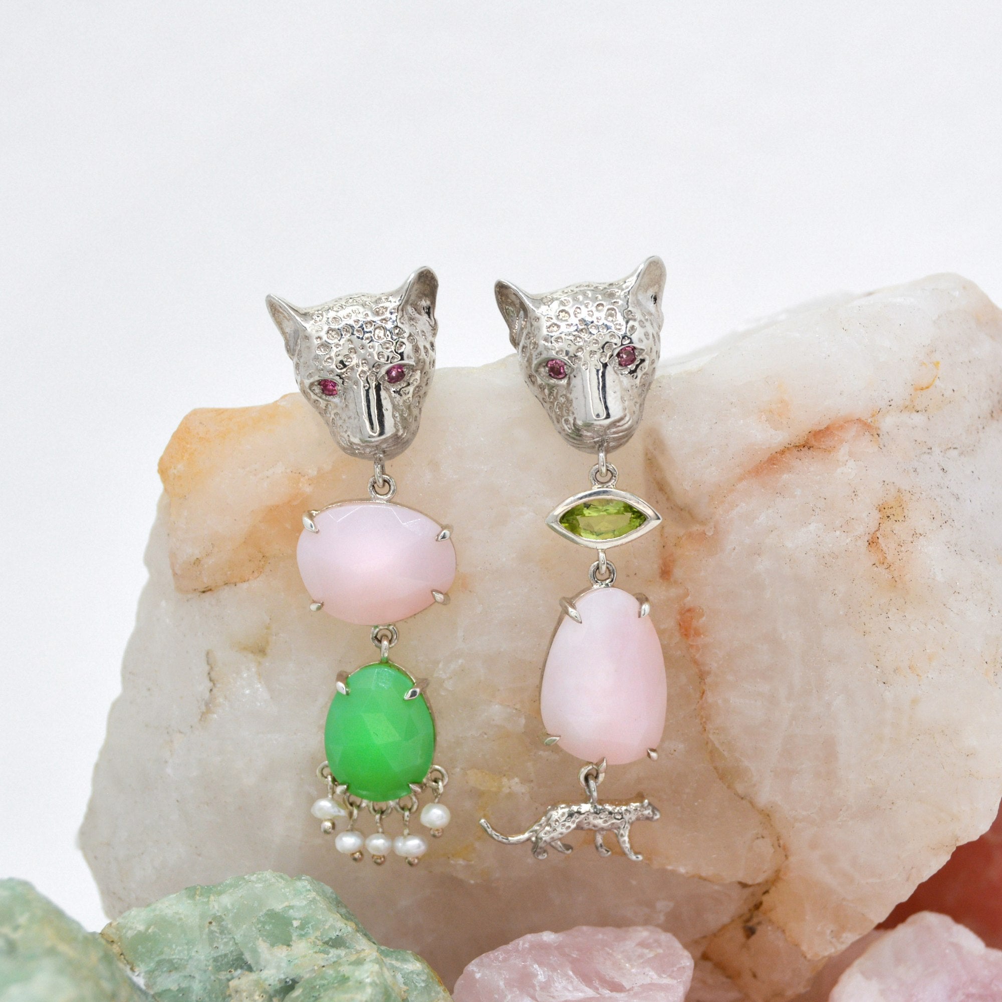 Pair of silver leopard earrings with gemstones on a stone background