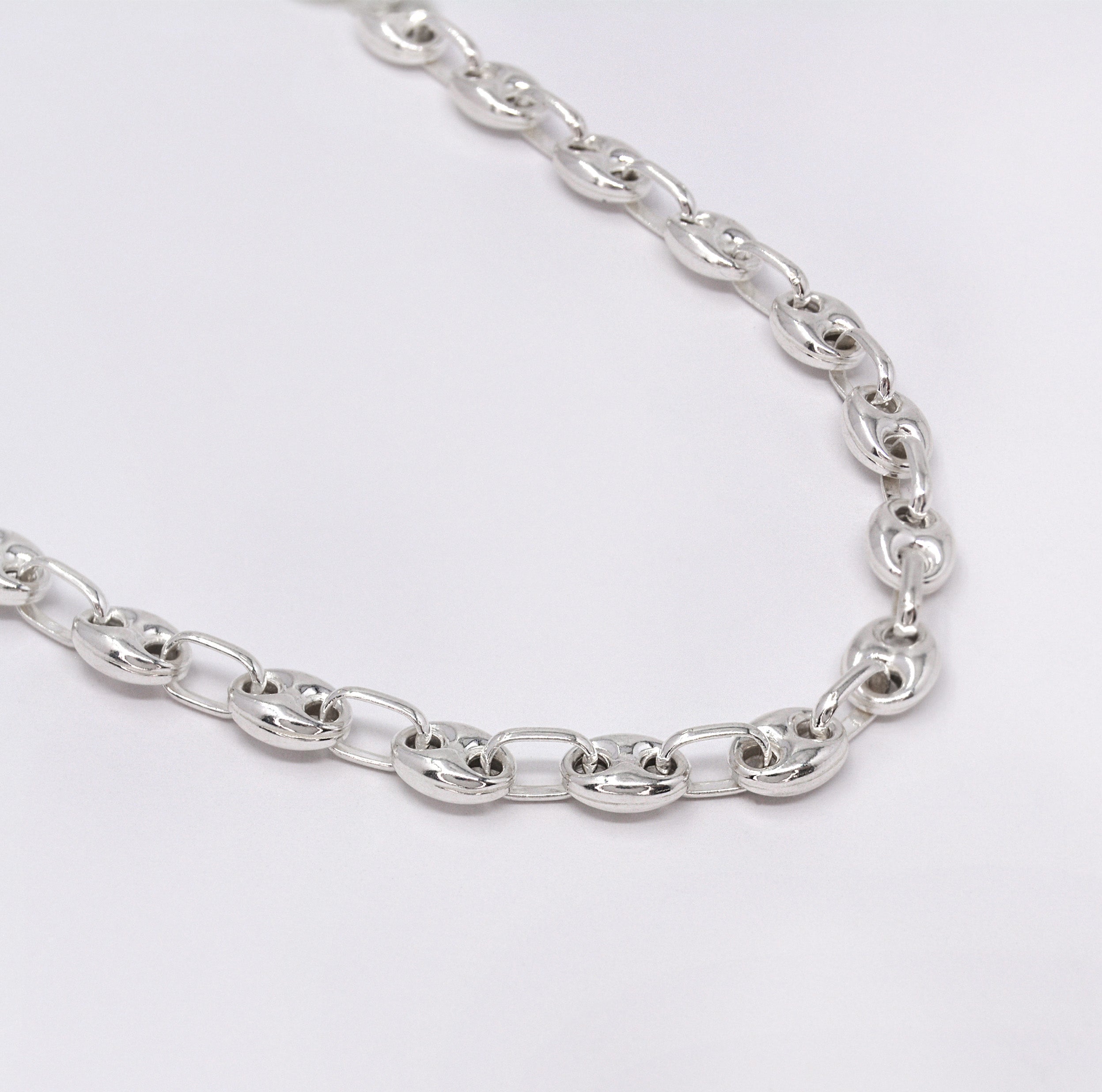 Silver chain necklace on a light gray background