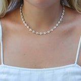 Silver Gucci chain necklace worn by a person with a white top