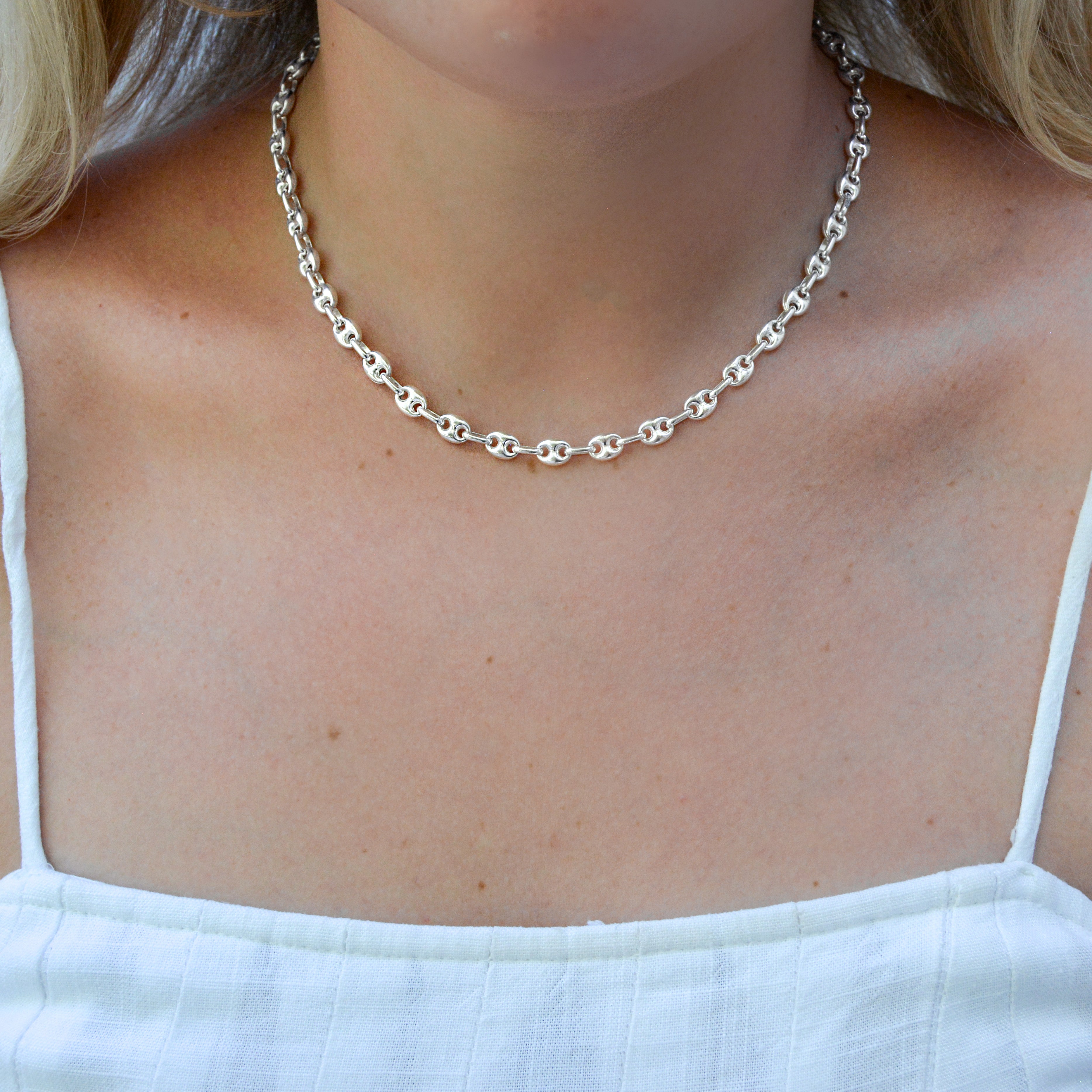 Silver Gucci chain necklace worn by a person with a white top