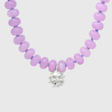 Close-up of the silver smiling sun charm hanging between lilac agate beads on lilac knotted thread