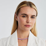 Model in a white blazer wearing the lilac agate necklace with its gold smiling sun charm