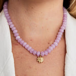 Lilac agate bead necklace with a gold smiling sun charm worn around the neck with a white shirt