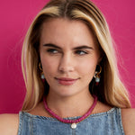 Model against a pink backdrop wearing the pink agate and wonky pearl necklace layered with a gold chain