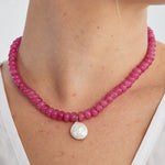 Vibrant pink agate bead necklace with a wonky pearl drop worn close around the neck