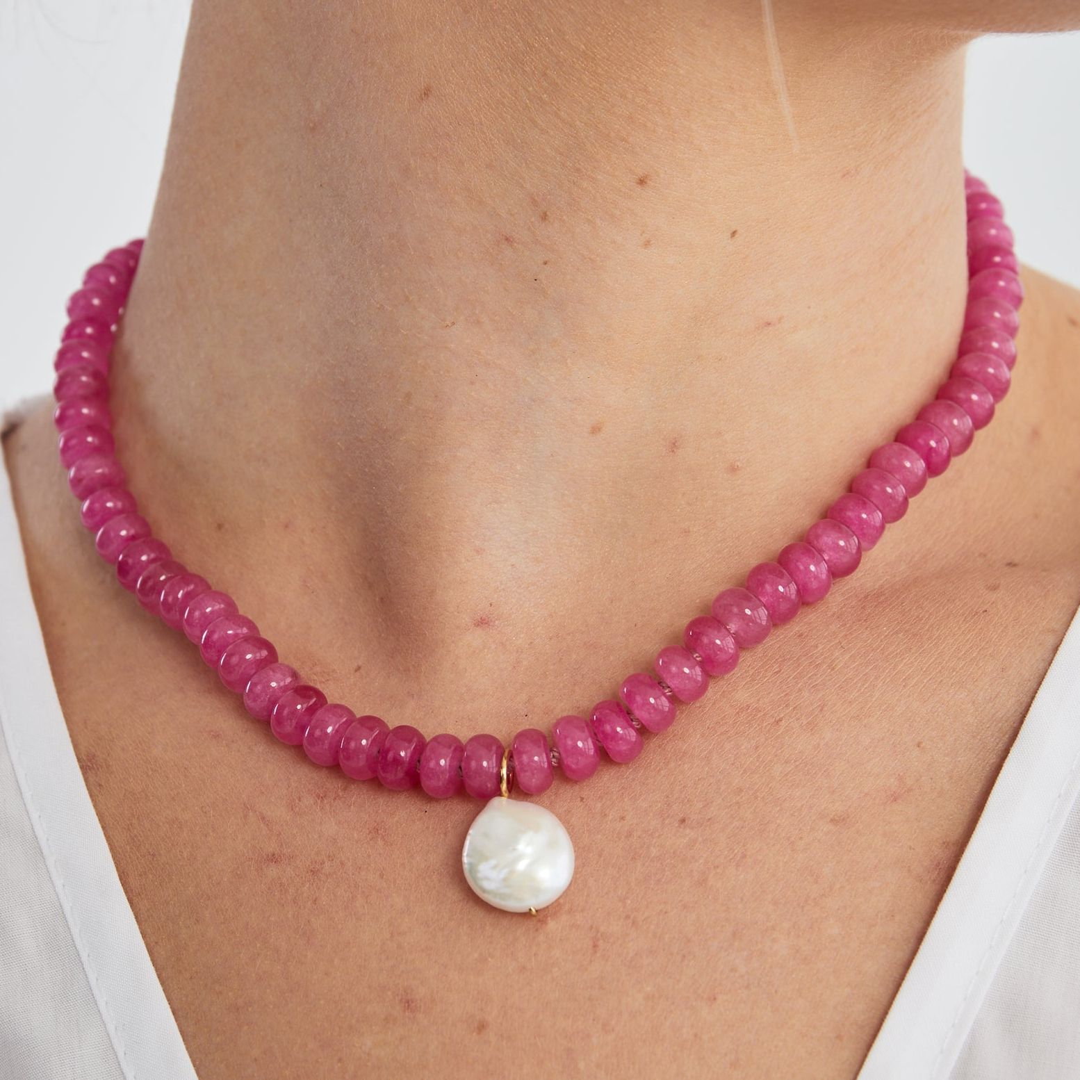 Vibrant pink agate bead necklace with a wonky pearl drop worn close around the neck