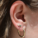 Opal, pink tourmaline and emerald cluster stud in gold worn on the earlobe above a gold hoop earring