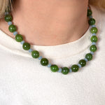 Green and blue beaded necklace worn by a person on a white background