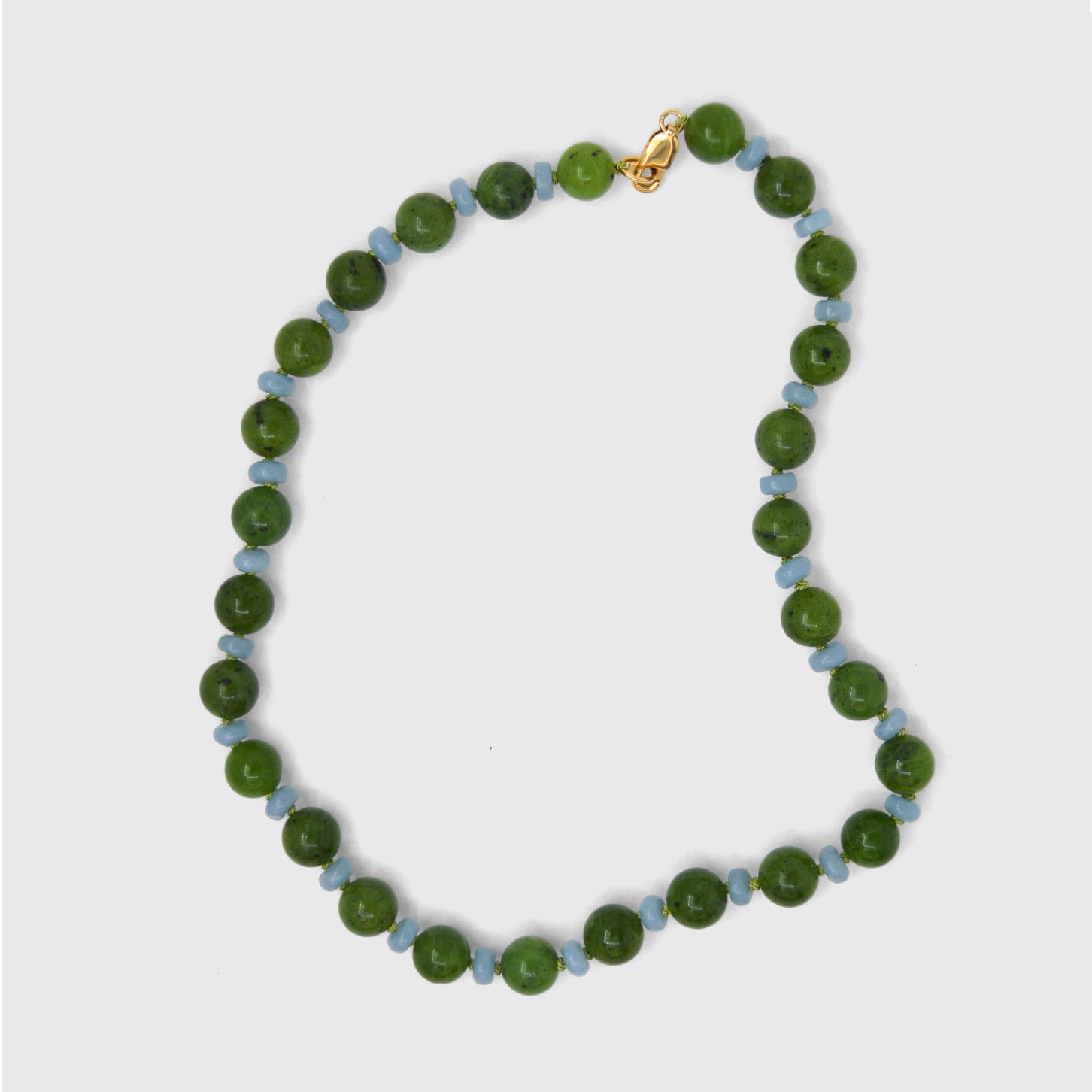 Necklace with blue and green beads on a light gray background