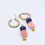 Two Cobalt Crush  charms, one hung on a gold hoop earring and one lying beside an open hoop