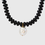 Necklace with black beads and a white pearl on a light gray background
