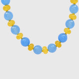 Close-up of round sky-blue jade beads alternating with butter-yellow agate rondelles on yellow knotted thread
