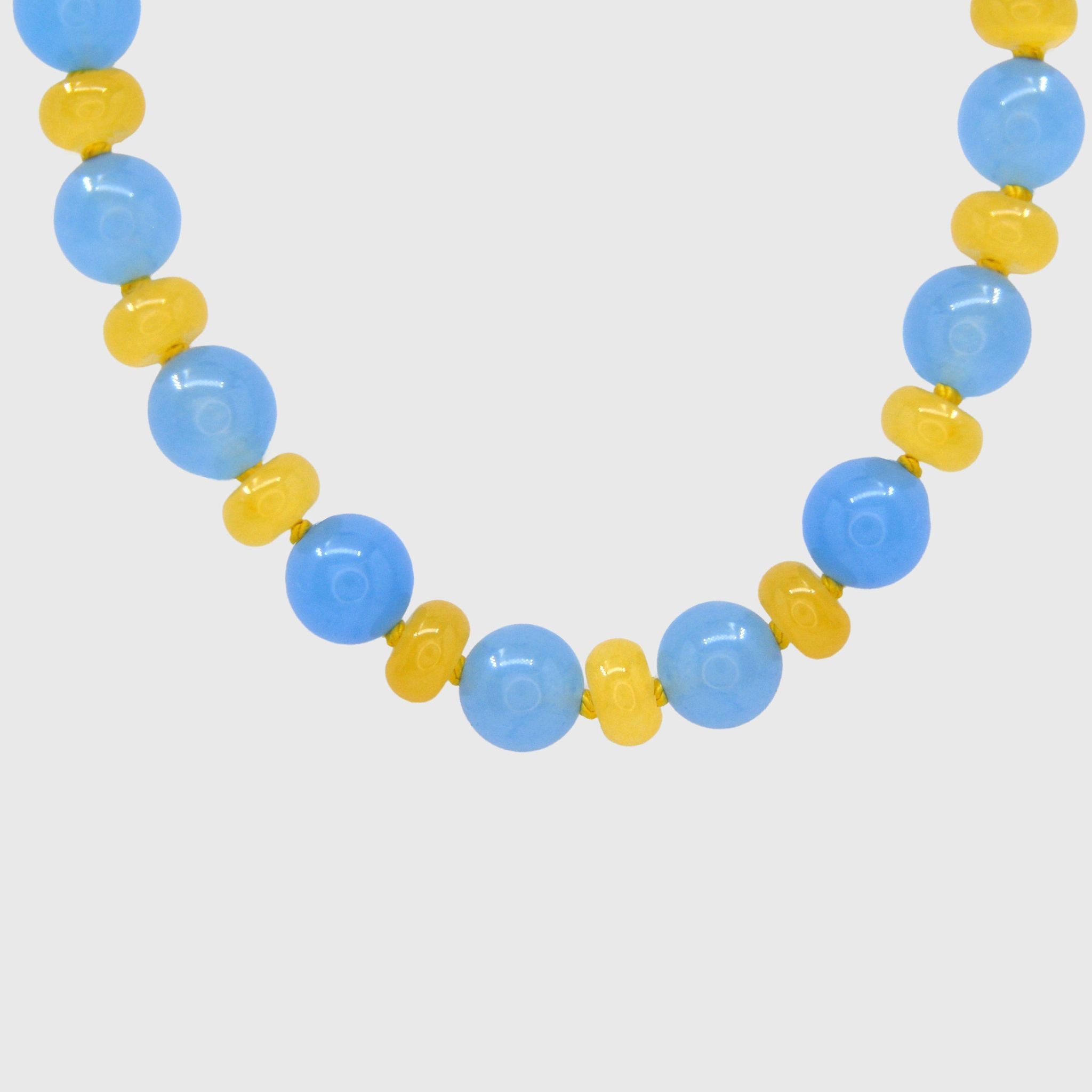 Close-up of round sky-blue jade beads alternating with butter-yellow agate rondelles on yellow knotted thread