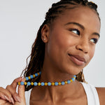 Smiling model holding the sky-blue jade and butter-yellow agate necklace away from her neck