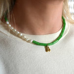 Jade beaded necklace with a gold initial pendant worn by a person 