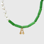 Necklace with jade and pearl beads and a gold pendant on a white background