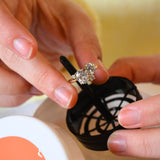 Person putting a diamond ring into a jewellery cleaning solution