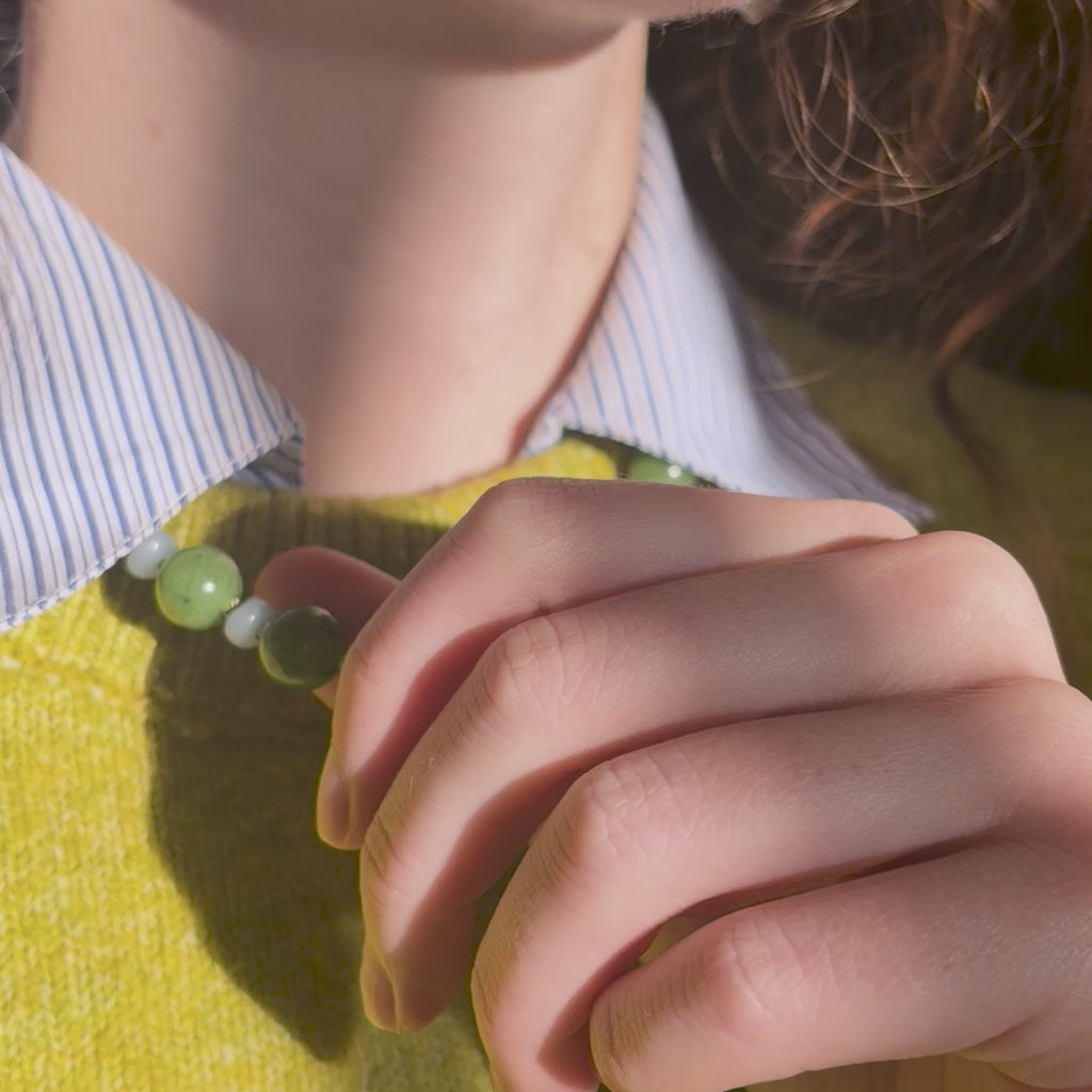 Green and blue beaded necklace worn by a person