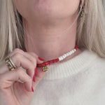 Necklace with coral beads and a gold moon pendant on a woman's neck 