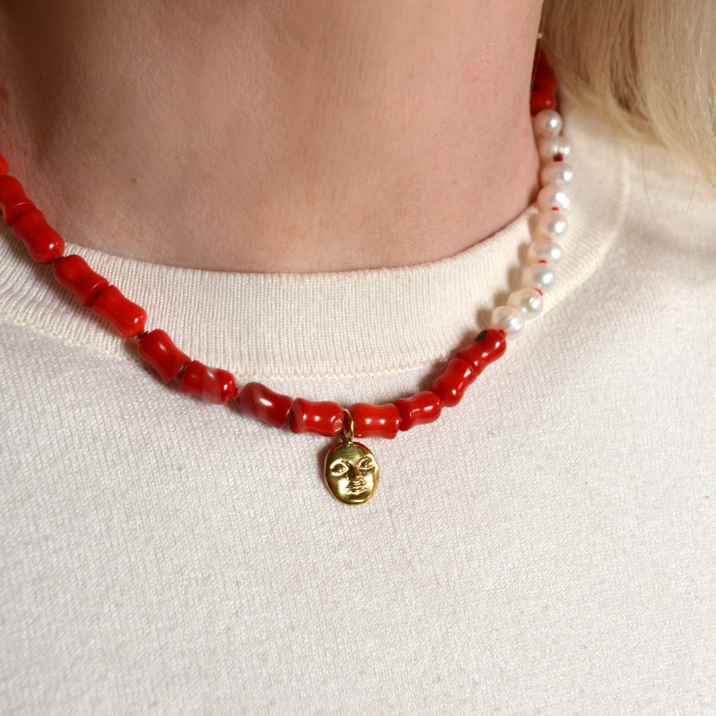 Necklace with coral beads and a gold moon pendant on a woman's neck 