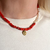 Necklace with coral beads and a gold moon pendant on a woman's neck 