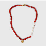 Necklace with coral beads, a gold clasp and moon pendant on a white background