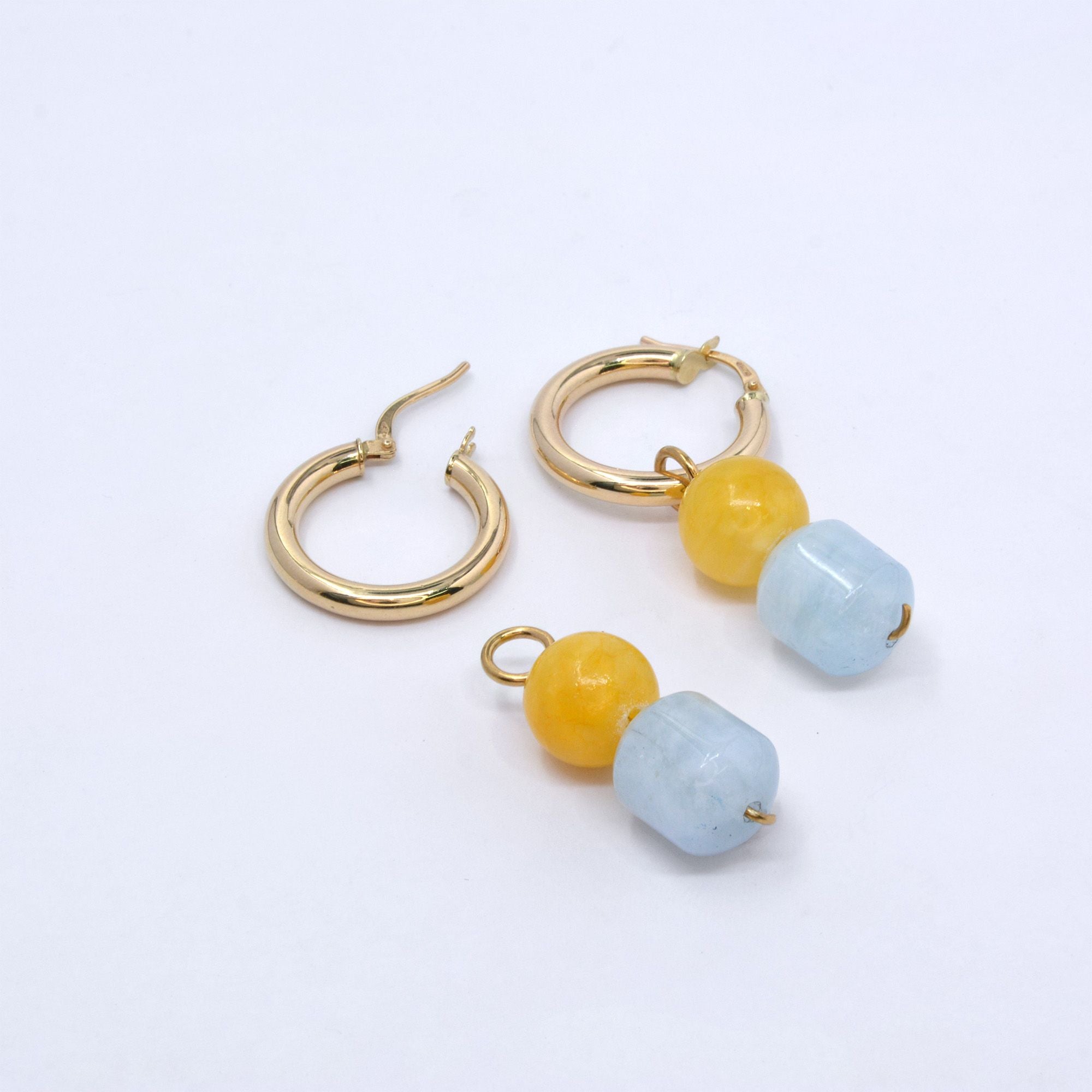 Two mango jade and aquamarine charms, one hung on a gold hoop earring and one lying beside an open hoop