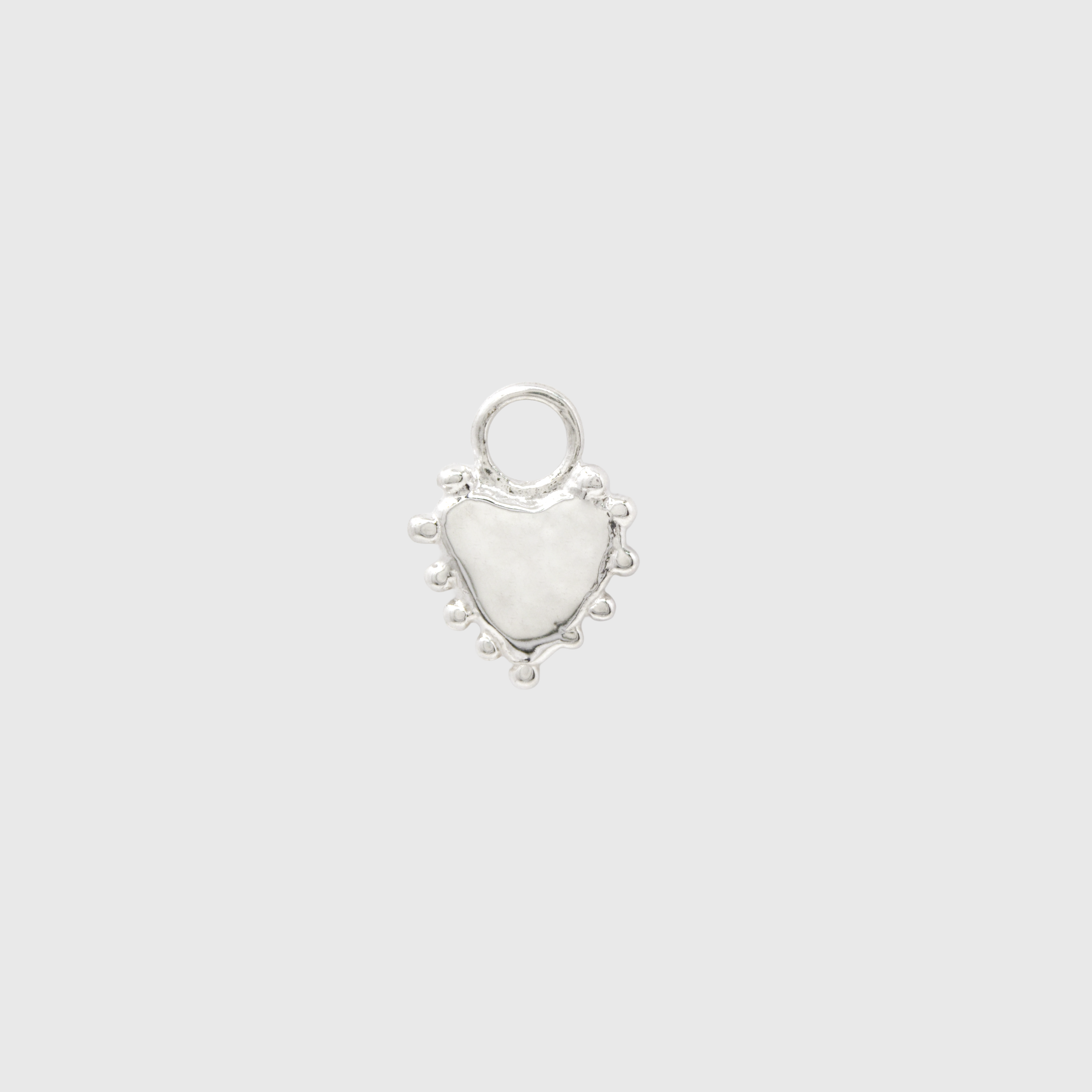 A small silver heart-shaped charm with a textured finish, a loop at the top, and small bead-like details along the outer edge, centered on a light gray background.
