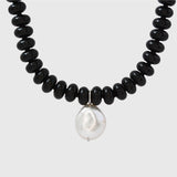 Necklace with black beads and a white pearl on a light grey background